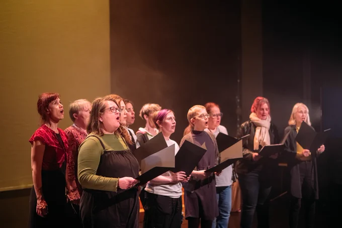 A group of people stand and sing on stage.