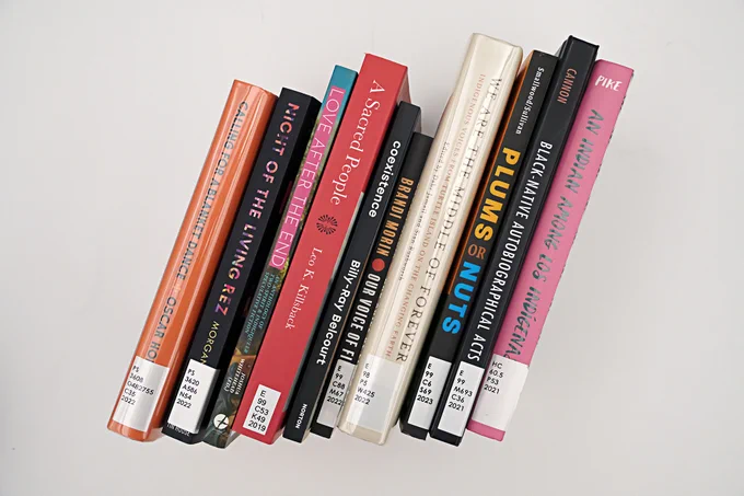 A row of books standing upright against a plain background, featuring a variety of spine colors and titles.