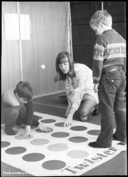 Two children playing Twister with an adult giving directions