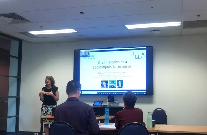 Catherine Travis presenting in front of title slide, 'Oral histories as a sociolinguistic resource'.