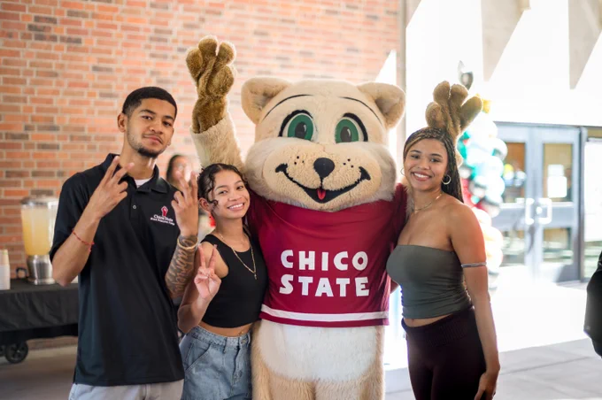 Three students pose fro a photo with Chico State's mascot, Willie the Wildcat.