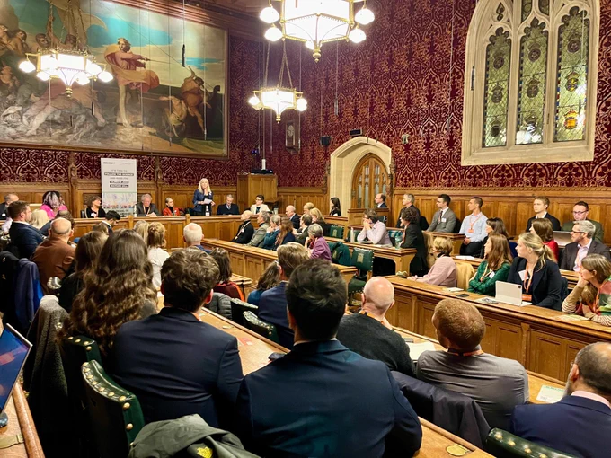 Large and ornate committee room in Parliament with cross party MPs, scientists and campaigners filling the seating. Lib Dem MP Roz Savage is speaking and Green MP Carla Denyer is nearby.