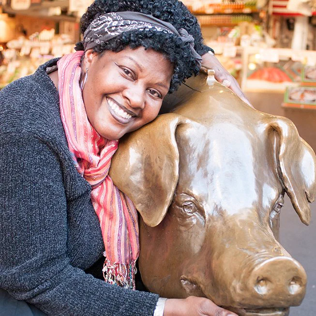 Sandra Dunn poses with an iconic bronze pig statue at Pike Place Market in Seattle, Washington. 