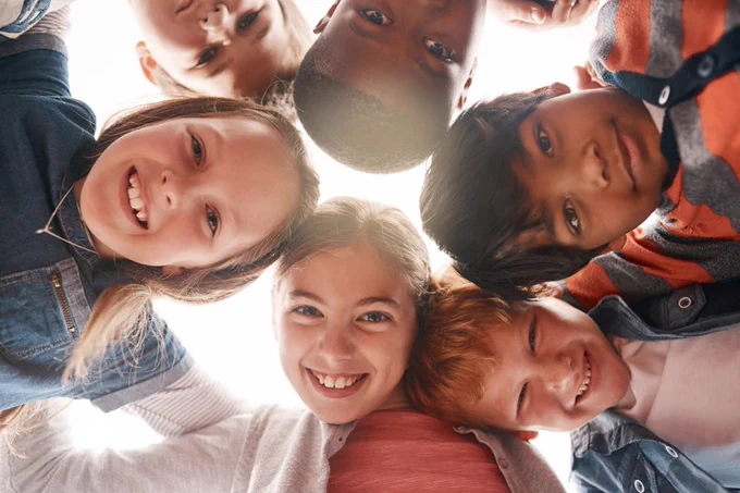 Group of children from different backgrounds touching heads and smiling together