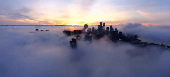 View from Space Needle webcam this morning at sunrise showing low clouds and fog surrounding Seattle with the Cascades in the distance.