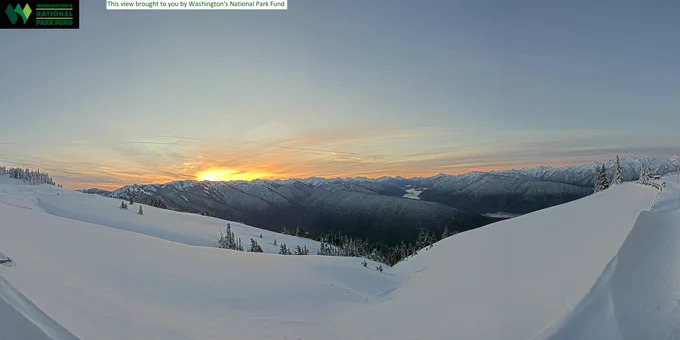 View from Hurricane Ridge with snow on the ground and mountains in the distance at sunrise.