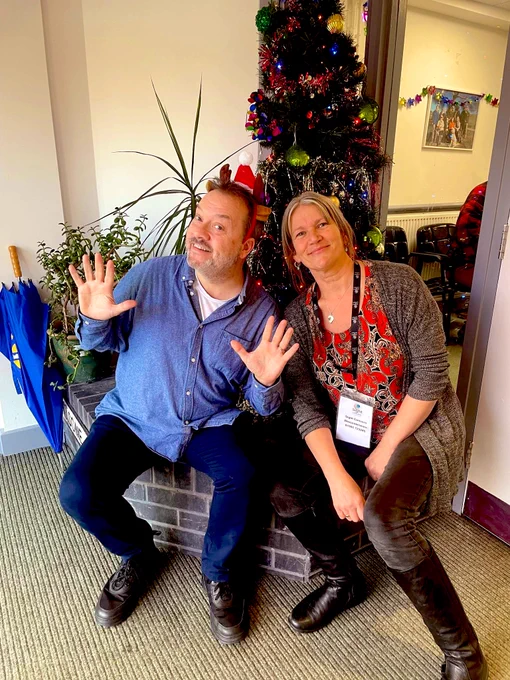 Two people smiling in front of a Christmas tree