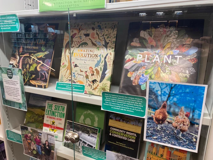 Image shows a book display with titles about plants and evolution along with photos and text about Roehampton initiatives