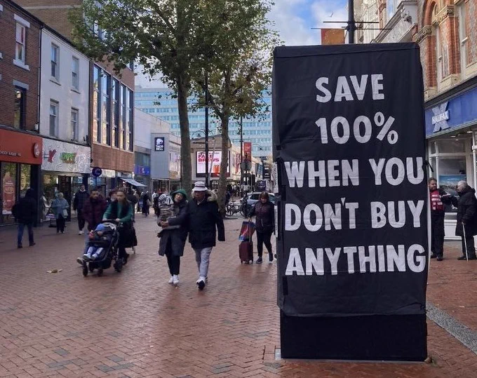 Street view with modified advertising board with words, “SAVE 100% WHEN YOU BUY NOTHING”