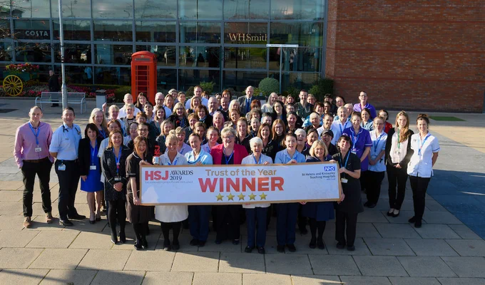 St Helens and Knowsley named Trust of the Year by the HSJ, staff stood outside Whiston Hospital