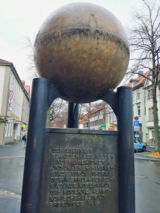 The artistic rendition of the sun is a big yellow metal ball. Below is the monument of the Planetenweg, explaining the artwork is dedicated to all children and to Göttingen's partner town Toruń, home of astronomer Copernikus.
