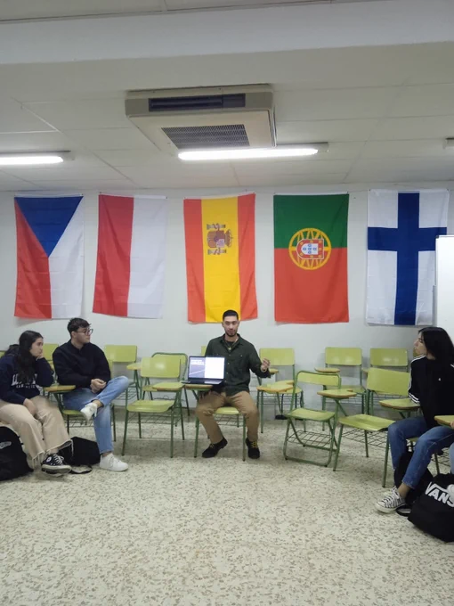 Students sitting in a classroom with country flags hanging on the wall