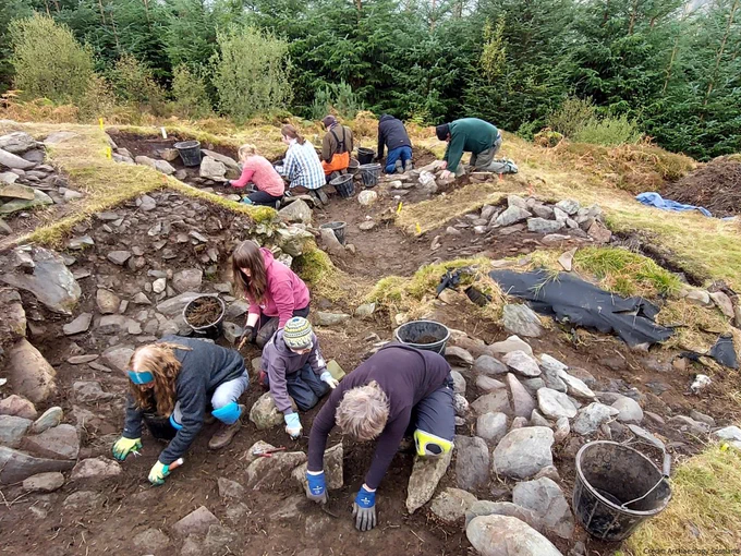 Photo of a group of people digging in an archaeological trench