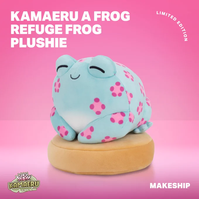 A blue frog with a pink flowery pattern is laying on a brown platform, the frog is smiling. It is a pink shiny background and the Kamaeru: A Frog Refuge logo in is the bottom right hand corner.