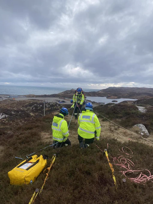 Three coastguard rescue officers setting up ropes