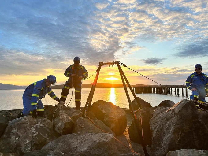 Two coastguard rescue officers setting up rope rescue equipment at the coast