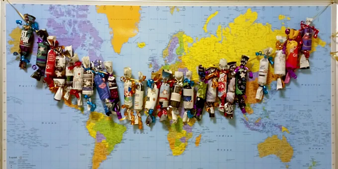 Advent calendar, made of toilet paper rolls and journal pages, in front of a map of the world.