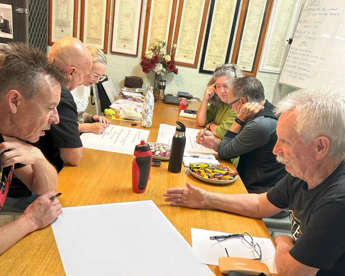 Photo of six people at a table in the midst of discussion. 