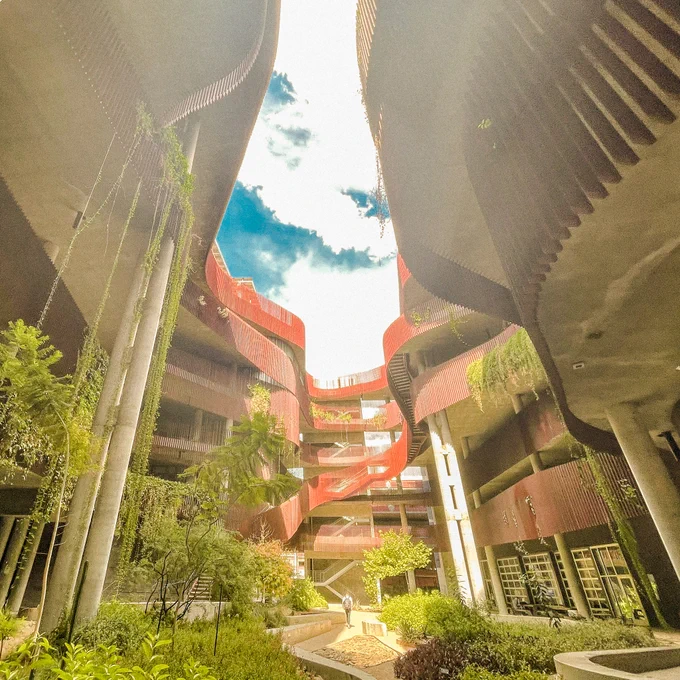 This image depicts an architectural view of a unique building with wavy, overlapping red balconies and walkways.