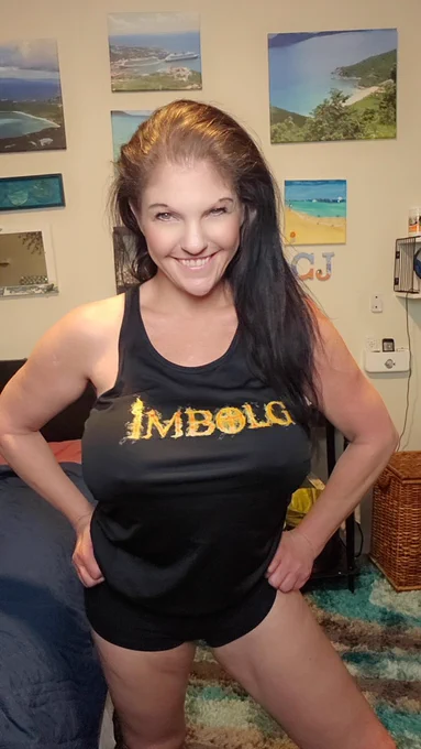Coralyn Jewel wearing a black Tank Top with Flame font letters that spell the word I M B O L G