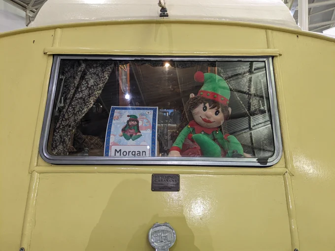 A Christmas elf looks out from a 1935 caravan window. 