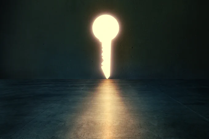 Dark room with a keyhole in the far wall that has light shining through it.