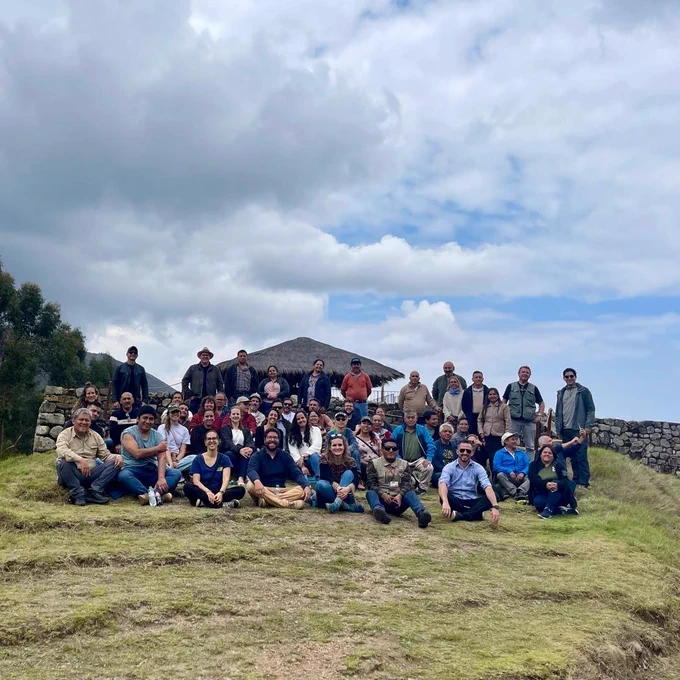 A large group of people posing on a hill top.  