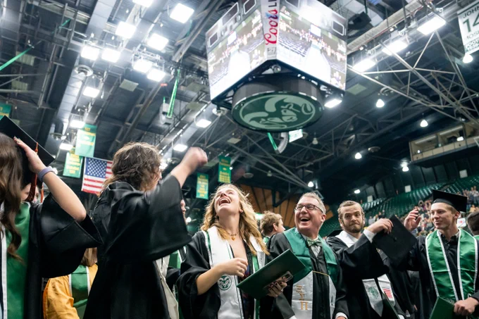 Graduates in Moby Arena standing and smiling during commencement.