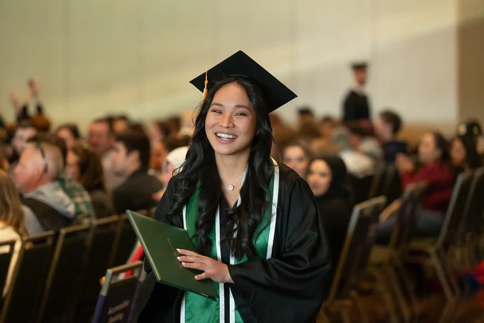A graduate walking and smiling after receiving their diploma in the Lory Student Center.