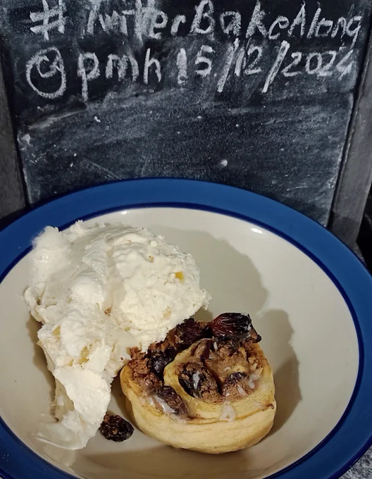 A fruit and nut pastry swirl in a bowl with a rough scoop of ice-cream