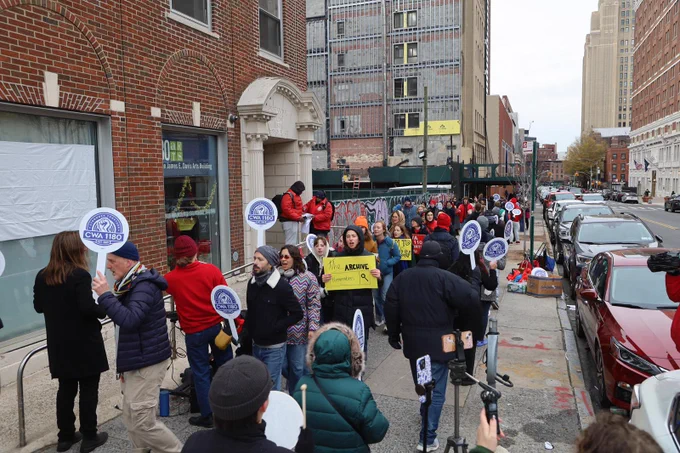 Picture of rally- people walking holding signs.