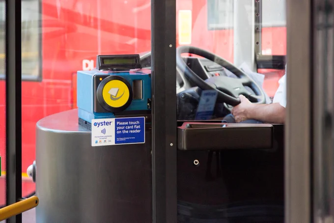 A yellow Oyster card reader at the entrance to a London bus.