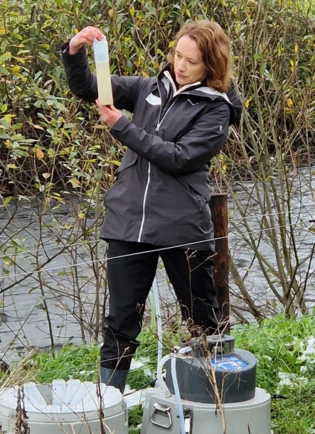 Farming for Water's Mairead Shore examining a water sample outdoors near a stream.