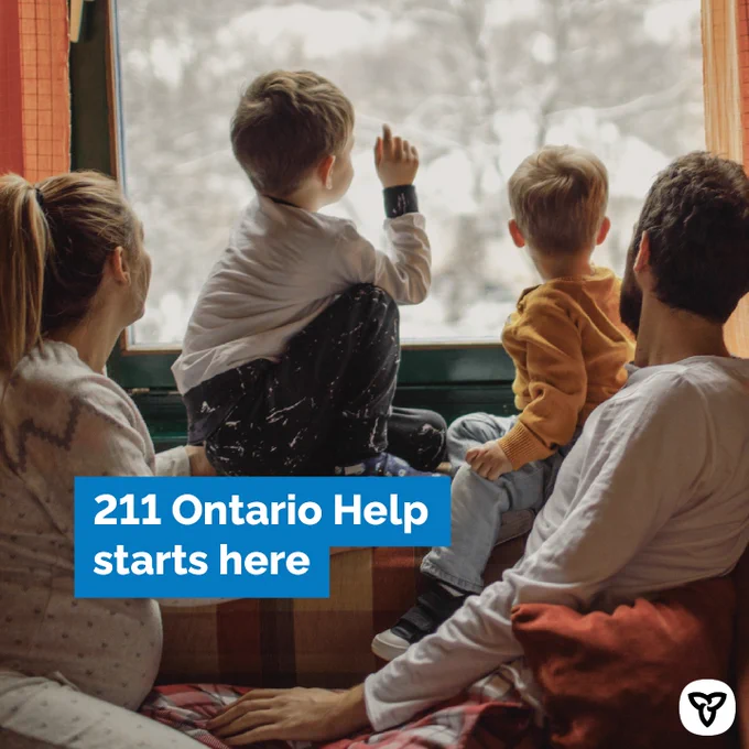 Parents with two kids looking out the window on snowy day