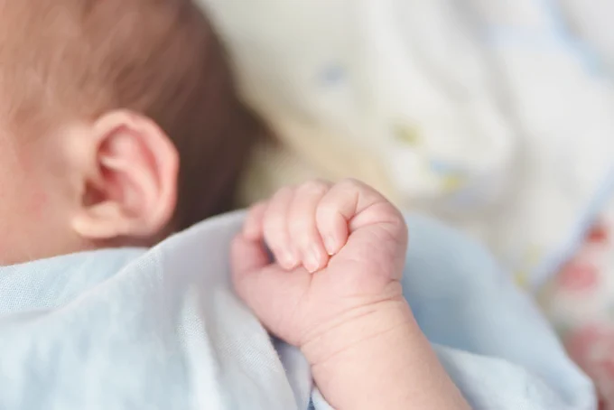 Image shows a newborn baby's hand and part of their head. Image designed by Freepik www.freepik.com