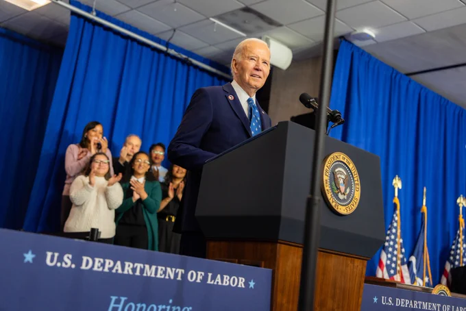 President Joe Biden speaking at a podium at the Frances Perkins homestead national monument dedication ceremony at the Department of Labor headquarters in a Washington, DC