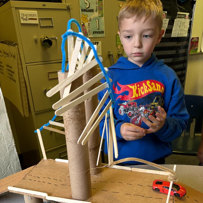 Student building a bridge out of cardboard and paper towel tubes