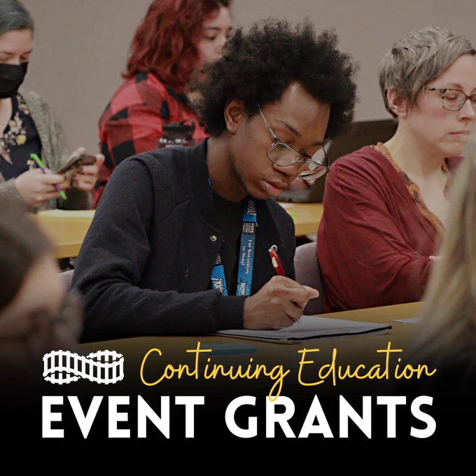 Rails continuing education event grants. A group of people sitting at a table, the person in front writing in a notebook. 