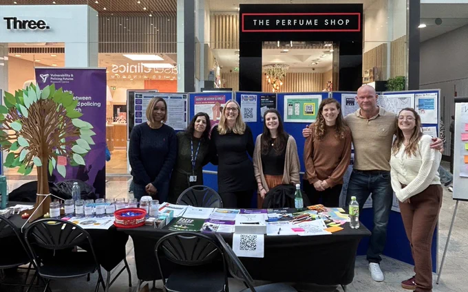 Group shot of researchers stood in front of poster boards in the Broadway Shopping Centre, Bradford.