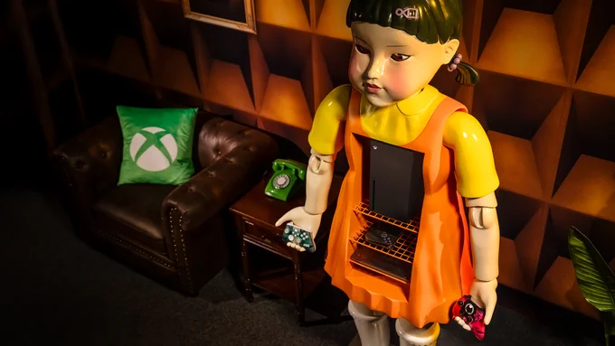  Image of the Squid Game Young Hee Gaming Cabinet next to a chair with a green Xbox pillow and side table with a green telephone.