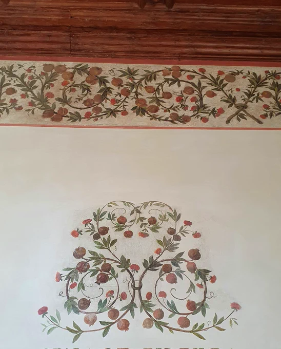 A painted design on the walls of the villa involving trailing vines, red flowers and pomegranates.
