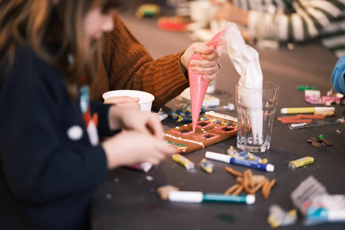 A child and parent work together to pipe icing on a gingerbread facade at Kids' Main Street 2023. Photo by Kurtis Chen.