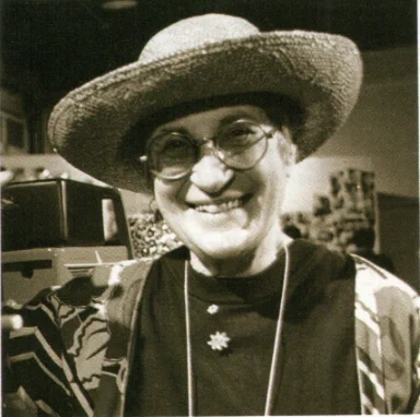 A photo from 1994 of Jean Johnson smiling broadly in sepia tone to match the other photo.
