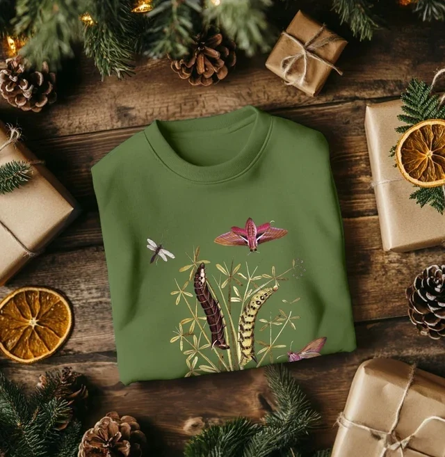 Elephant hawk moth jumper in green surrounded by wrapped gifts, dried citrus and Christmas wreath