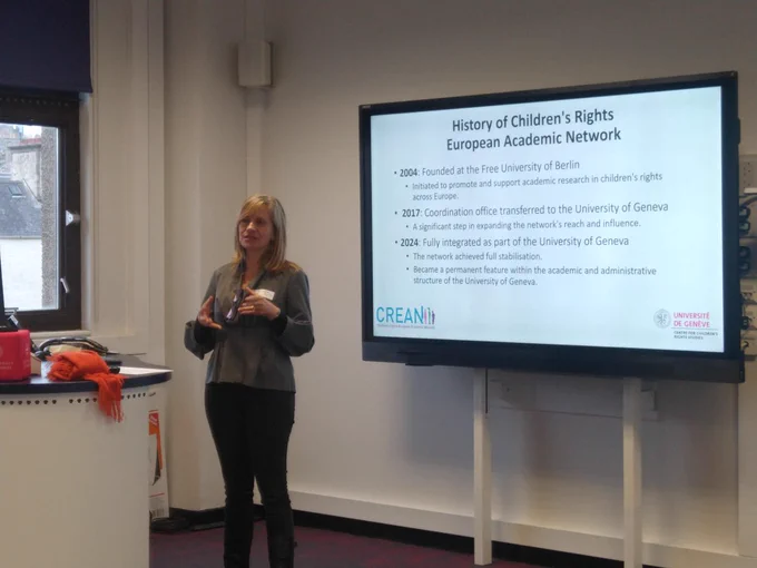 Dr Roberta Ruggiero is standing in front of a screen showing slides and speaks to the audience about the history of the Children's Rights European Academic Network