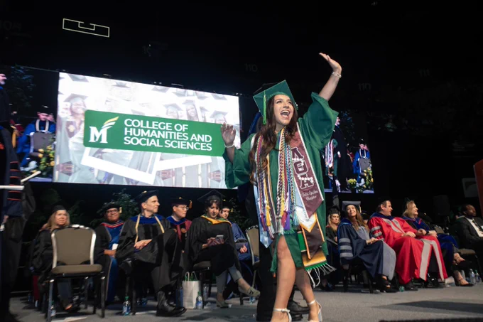 George Mason CHSS student walks across the stage at graduation.