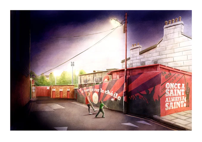 A scene from street level outside Richmond park at night time. Two kids playing football against the mural wall under a street lamp.
