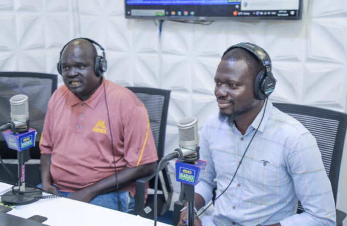 Two men- Gender Activist, Lam Deng and Data Gordon- speak on Eye Radio’s Dawn Show. They are sitting in front of microphones and wearing headphones at EyeRadio's podcast station as they are being interviewed. Location is South Sudan. November 19, 2024. (Photo Credit: Lou Nelson/Eye Radio). 