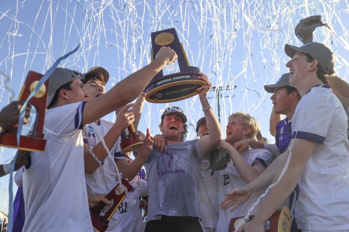 Members of the Amherst College men's soccer team joyfully holding up the NCAA Championship trophy amid a spray of confetti.