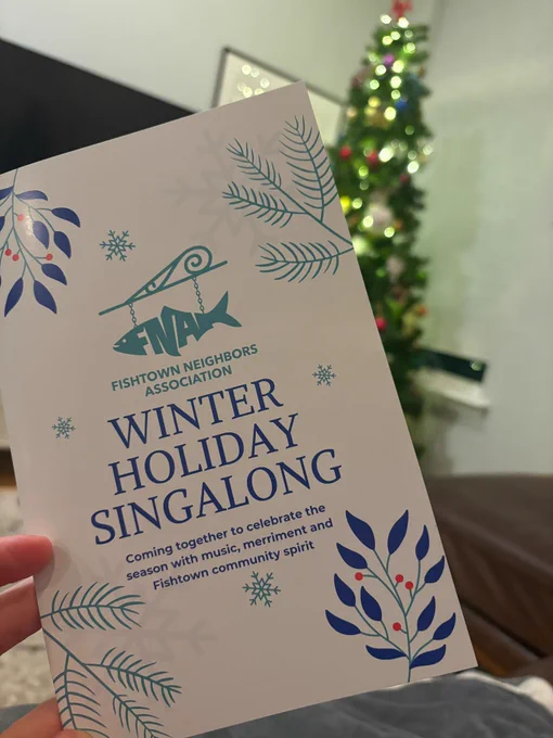A picture of the Winter Holiday Singalong songbook, taken in front of a beautiful Christmas tree.